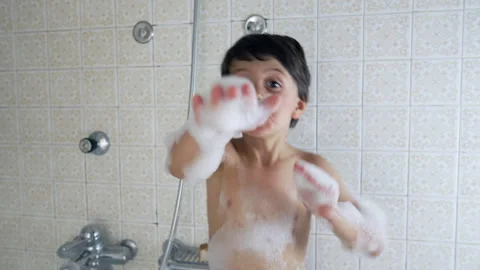 Smiling boy enjoying a bath with soap bubbles, arms raised and covered in f.. Stock Footage 276821502