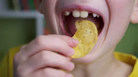 Smiling boy enjoys chips. Young caucasian kid eating unhealthy potatoes crisps. Vídeo Stock 133266660