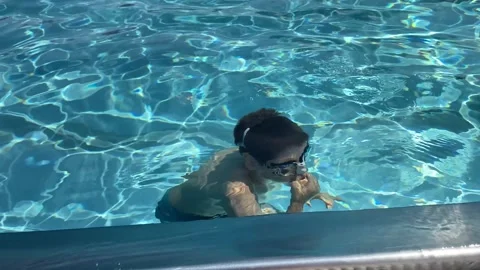 Smiling boy in goggles holds nose to dive in swimming pool and talks to camera Stock Footage 341400809