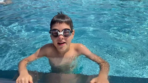 Smiling boy in goggles talking directly to camera in swimming pool Stock Footage 341400776