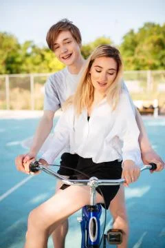 Smiling boy happily looking in camera while riding on bicycle with beautiful Stock Photos