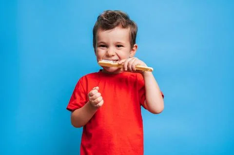Smiling boy with healthy teeth brushing his teeth with a toothbrush on a blue Stock Photos