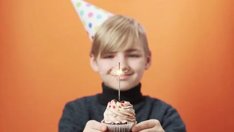 Smiling boy holds a cupcake with a burning sparkler in his hands. Video stock 164367127