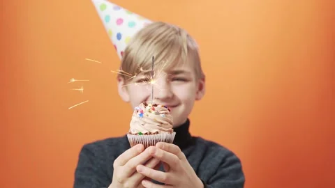 Smiling boy holds a cupcake with a burning sparkler in his hands. Stock Footage 164380255