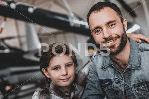 Smiling boy hugging satisfied bearded parent inside Stock Photos