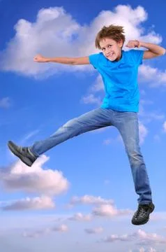 Smiling boy jumping and dancing in blue cloudy sky Stock Photos
