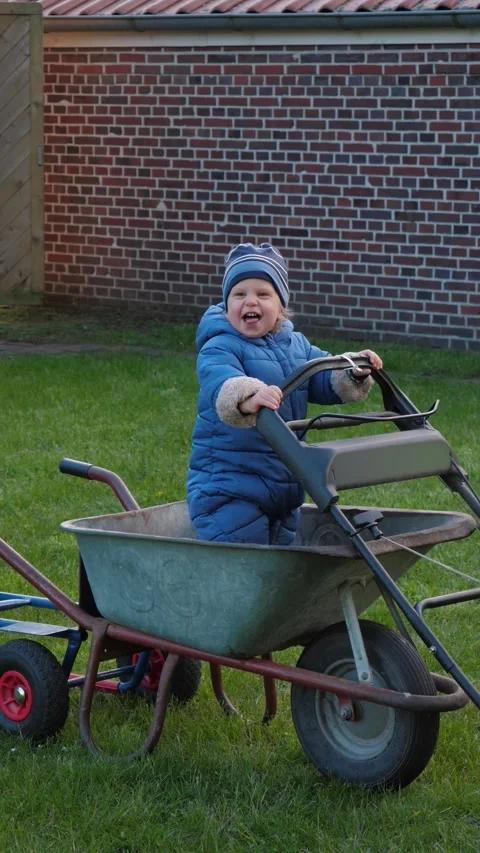 Smiling boy with Lawn Mower and Wheelbarrow Stock Footage 323331659