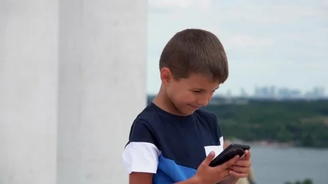 Smiling boy looking at smartphone against the backdrop of Paris in the distance Stock Footage 249251549