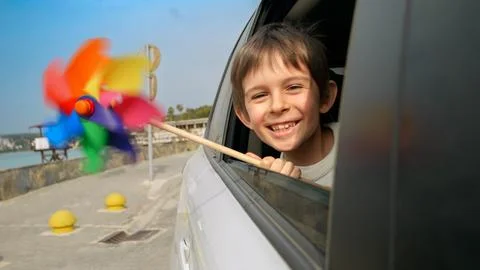 Smiling boy looking through open car window and holding colorful spinning p.. Stock Photos