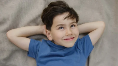 Smiling boy lying on blanket in backyard and looking at sky Stock Footage 119990537