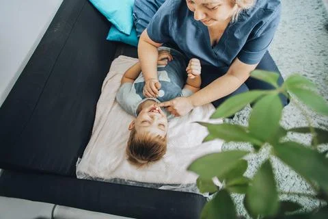 Smiling boy lying on blanket during a therapy session with a female specialist Stock Photos