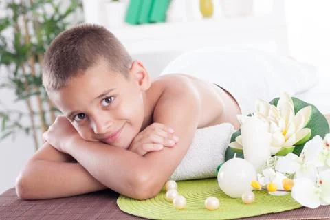 Smiling boy lying on the massage table in spa saloon Stock Photos