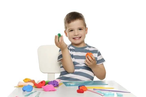 Smiling boy with play dough handiwork at table on white background Stock Photos