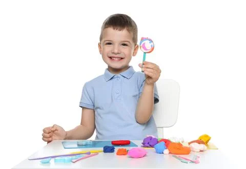 Smiling boy with play dough handiwork at table on white background Stock Photos