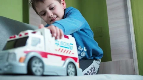 A smiling boy plays with an ambulance on the couch. children's imagination is a Stock Footage 146909585