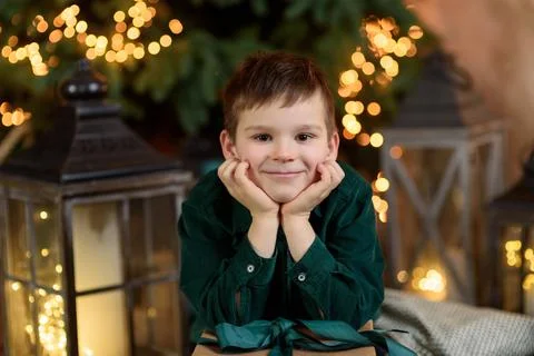 Smiling boy with present gift box sitting near stylish decorated Christmas tree. Foto stock