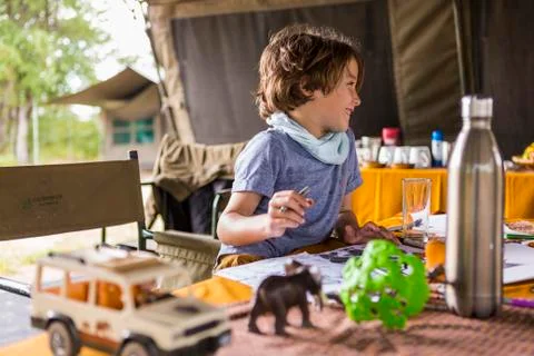 Smiling boy, profile, in a tented camp, on safari, playing with safari animal Stock Photos