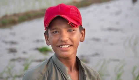 Smiling boy in red cap standing near rice field Stock Photos