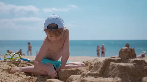 Smiling boy sitting and play with sand on the beach Stock Footage 138259860