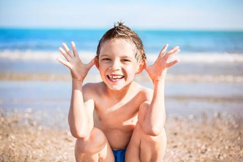 Smiling boy sitting on the beach Stock Photos
