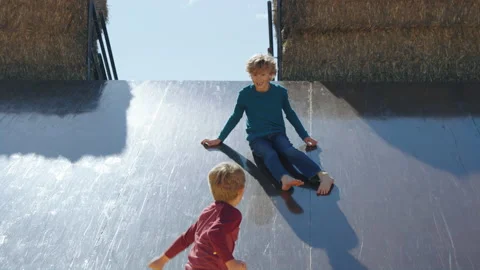 Smiling boy slides into corn pile, colliding with younger brother Stock Footage 202233408
