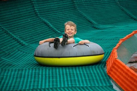 Smiling boy slides down in inflatable ring Stock Photos