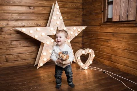 A smiling boy standing inside a decorated wooden house and holding a toy Stock Photos