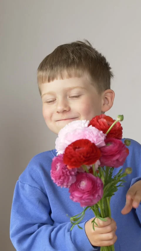 Smiling boy talks while holding a bouquet of bright ranunculus flowers, sharing Stock Footage 335144589