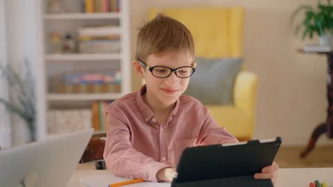 Smiling boy using tablet computer for browsing internet on distant learning Stock Footage 128972456