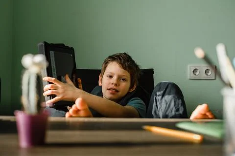 Smiling boy using tablet at home, growing up with technology Stock Photos