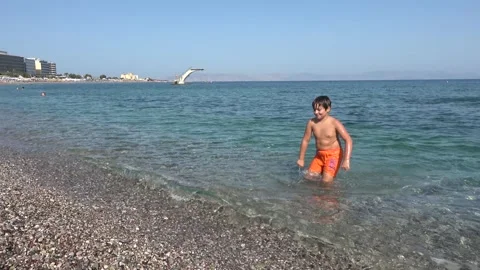 Smiling boy walking out of the sea onto Elli Beach in Rhodes Stock-Footage 342728253