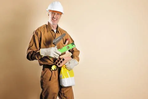 Smiling bricklayer holding tools and building materials brown isolated back.. Stock Photos