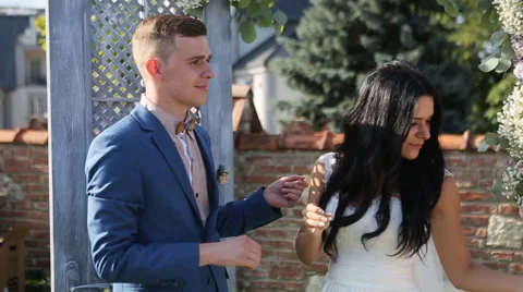 Smiling brunette bride putting wedding ring on groom during outdoors wedding Stock Footage 66003440