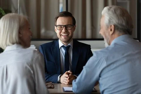 Smiling businessman manager in glasses consulting mature couple at meeting Stock Photos
