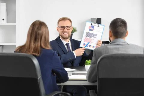 Smiling businessman presenting financial data and charts on a clipboard to co Stock Photos