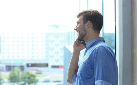 Smiling businessman standing and using mobile phone in office. Stockfoto's