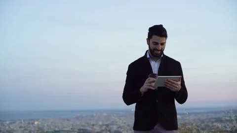 Smiling businessman in suit using tablet and drinking coffee outdoors Stock Footage 133375530