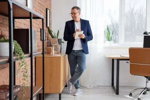 Smiling businessman taking notes in modern home office, productivity and remo Stock Photos