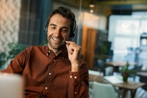 Smiling businessman talking on a headset while working late Stock Photos