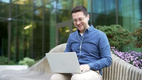 Smiling businessman talking on a video call using laptop while sitting  Stock Footage 307492402