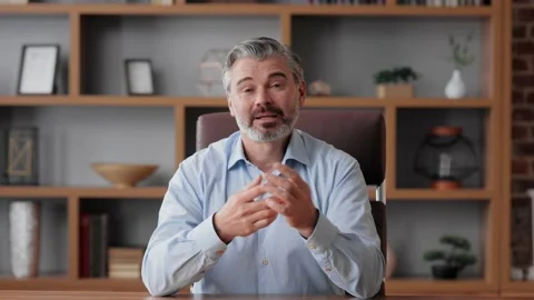 Smiling businessman talking to web camera sitting in office. Recording vlog 스톡 동영상 196926208