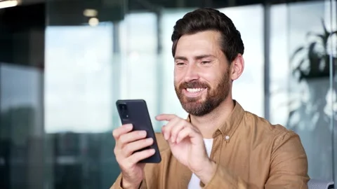 A smiling businessman is using browsing mobile phone at the workplace in a moder Stock Footage 316678877