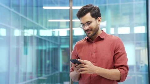 Smiling businessman is using, browsing smartphone while standing in business Stock Footage 297091597