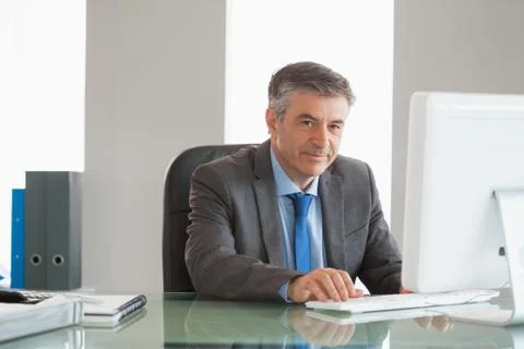 Smiling businessman using computer at office Stock Photos