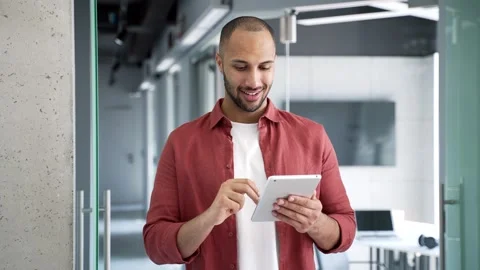 Smiling businessman is using digital tablet while standing in a modern business  Stock Footage 311623188