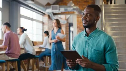 Smiling Businessman Using Digital Tablet Working In Busy Modern Open Plan Office Stock Photos