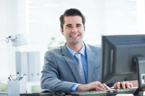 Smiling businessman using his computer Stock Photos