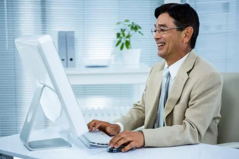 Smiling businessman using his computer Stock Photos