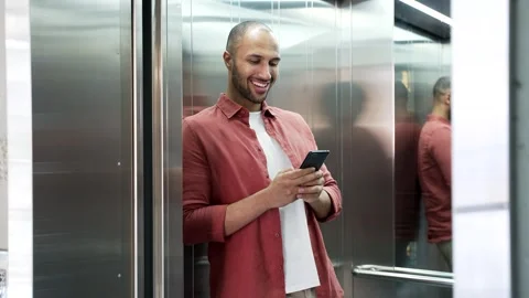 Smiling businessman is using mobile phone while standing in the elevator Stock Footage 311623409
