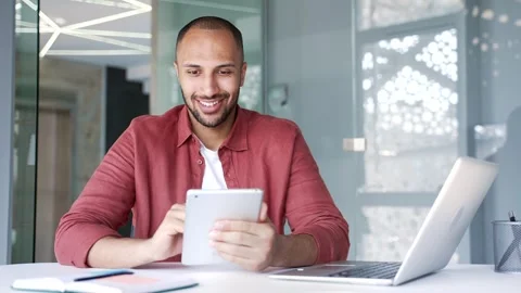 Smiling businessman is usingdigital tablet while sitting at workplace in modern  Stock Footage 311622856